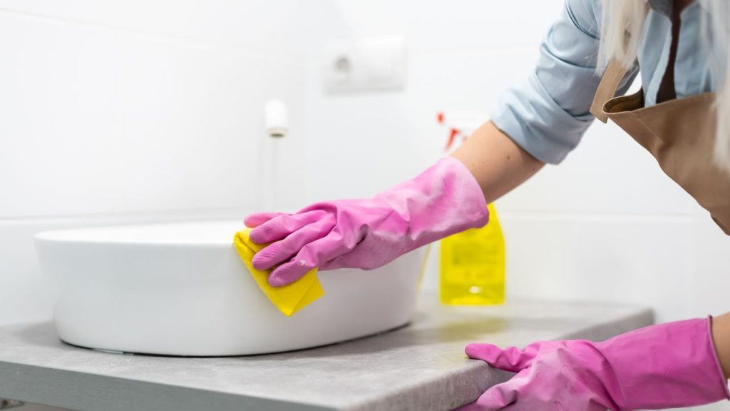cleaning inspection: housekeeper wearing pink nitrile gloves cleaning sink