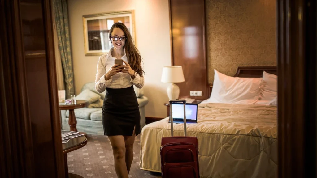 day use hotels near las vegas airport: women checking her phone while walking in her hotel room