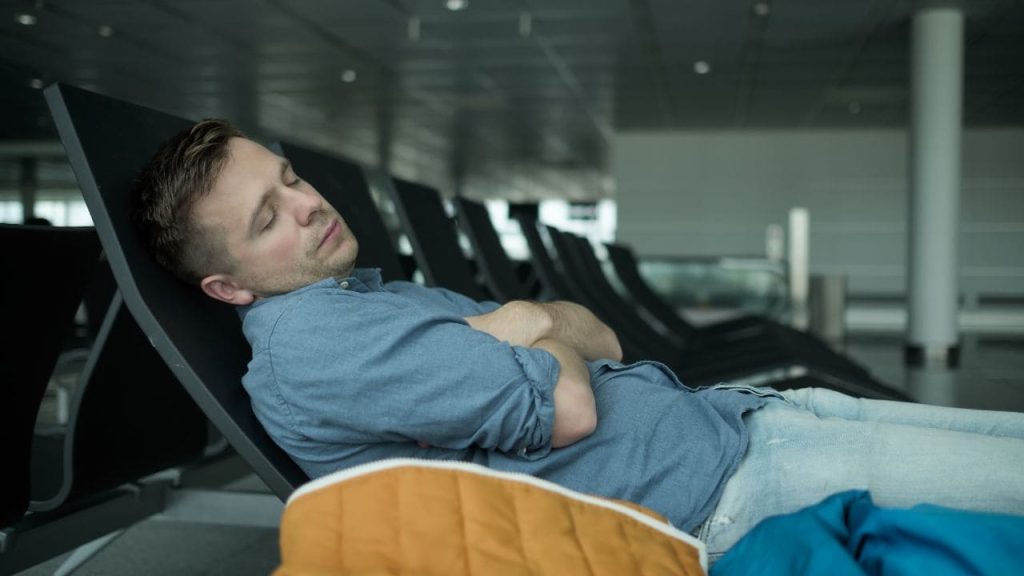 man sleeping in airport terminal in chair