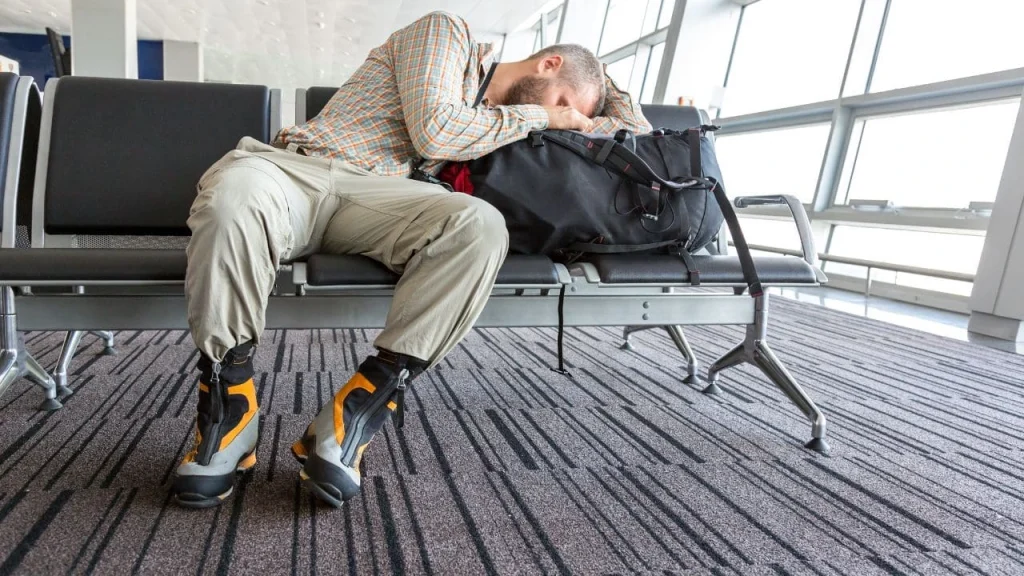man sleeping in an uncomfortable position in airport terminal