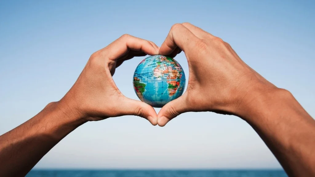 hands in the shape of a heart around a globe