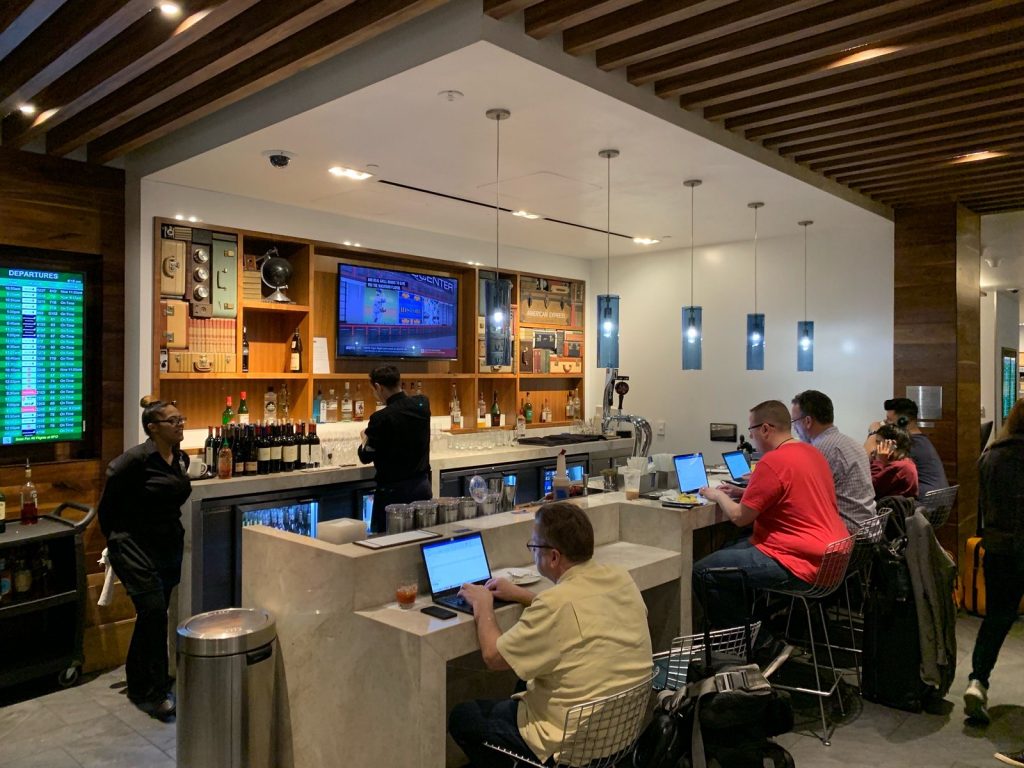 Business people and travelers work with drinks in hand at the AmEx Centurion Lounge in San Francisco International Airport.
