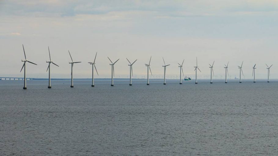 A danish offshore wind farm in Baltic Sea with ship passing in the distance.