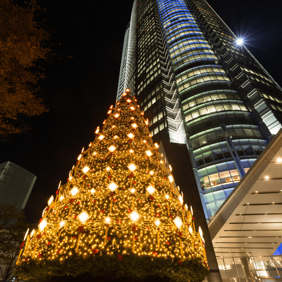 Giant Christmas tree lit up before a modern skyscraper at night in Roppongi, Tokyo, Japan.
