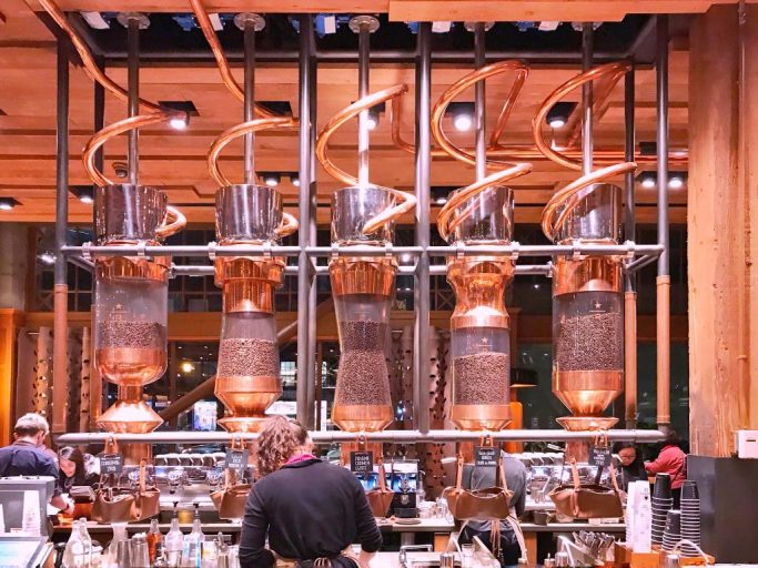 Giant copper coils wind down from the ceiling in coffee roastery. 