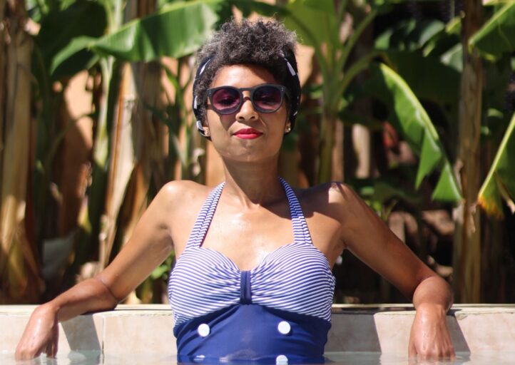 Woman relaxes in hotel pool with sunglasses on.