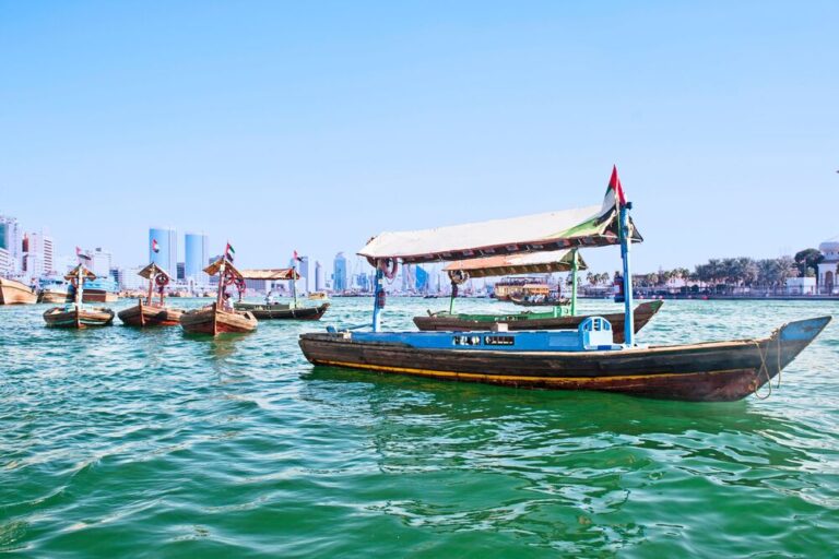 A traditional wooden abra boat with a canopy on the calm waters of Dubai Creek.