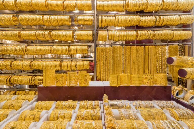 Shelves of ornate gold bracelets and necklaces on display in a Dubai souk.