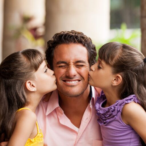 a pair of Latin girls kissing their father on the cheek.