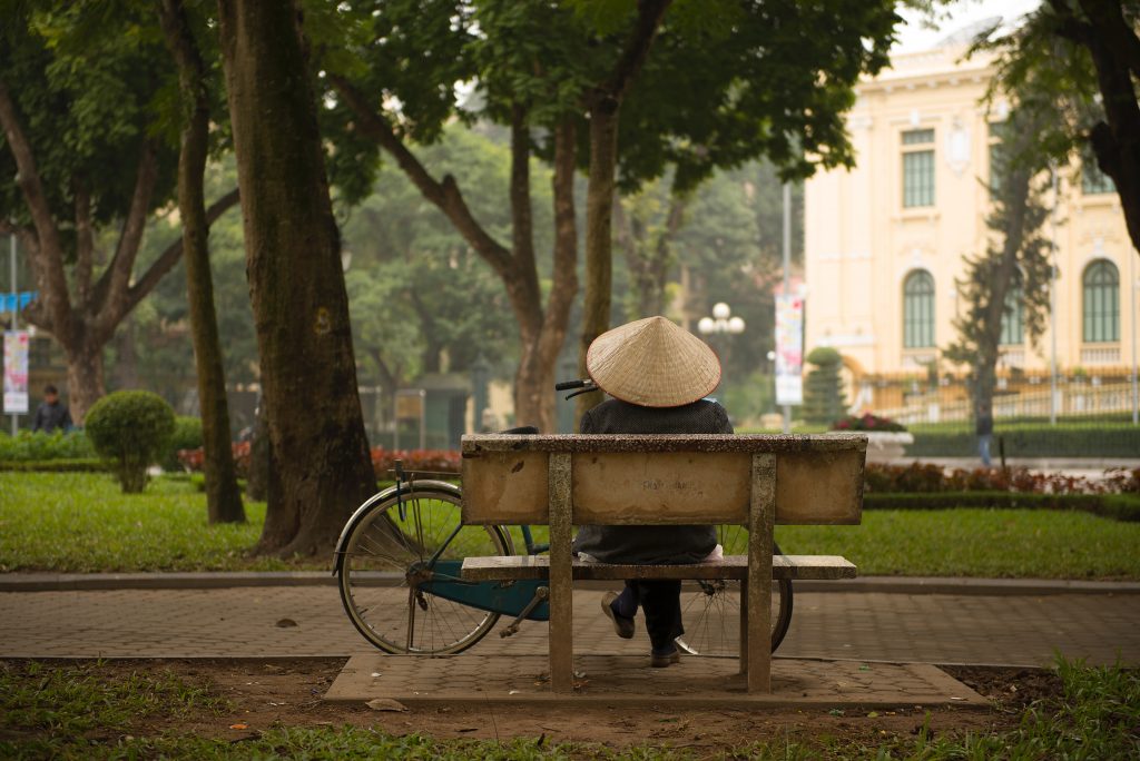 Person sits on bench in peaceful park in Hanoi, Vietnam