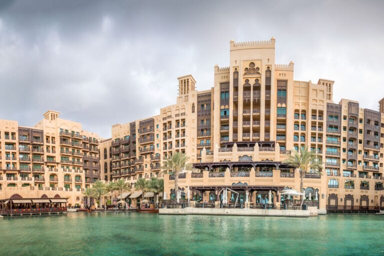 Madinat Jumeirah's waterfront with traditional architecture under overcast skies.