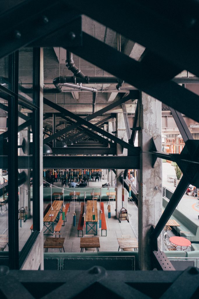 Side view of Ponce City Market in Atlanta framed through steel cross beams on a neutral overcast afternoon.