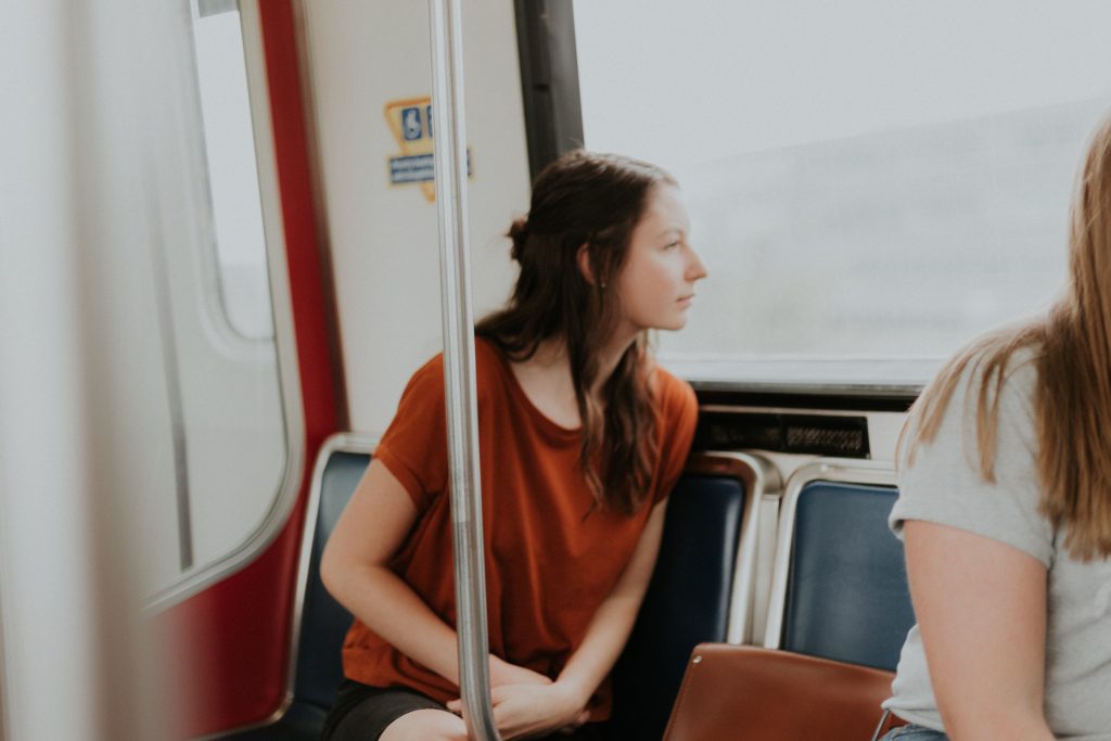 Woman excitedly looks out window on public transportation while exploring a new city.