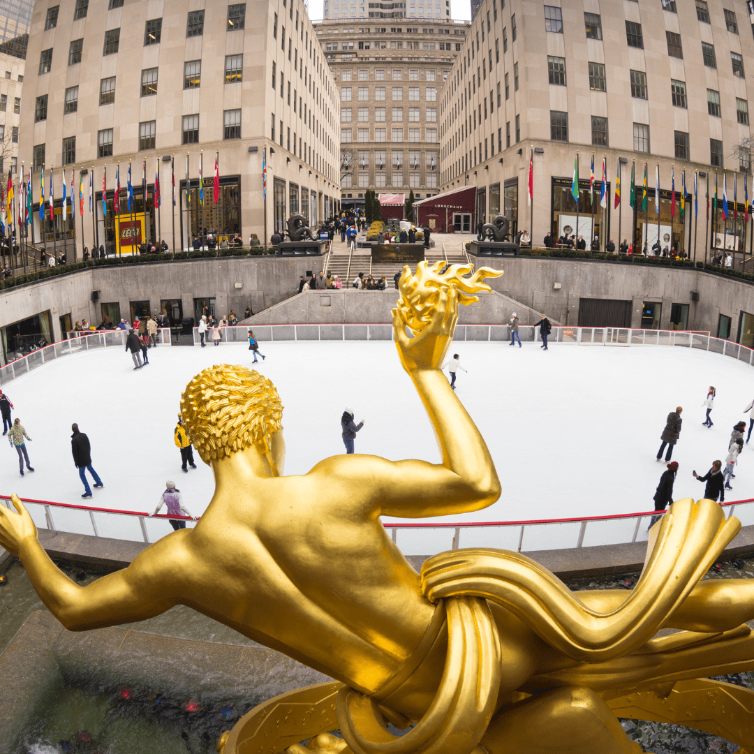 Skaters on Rockefeller Center's ice rink in NYC, with the golden Prometheus statue foregrounding the bustling scene.