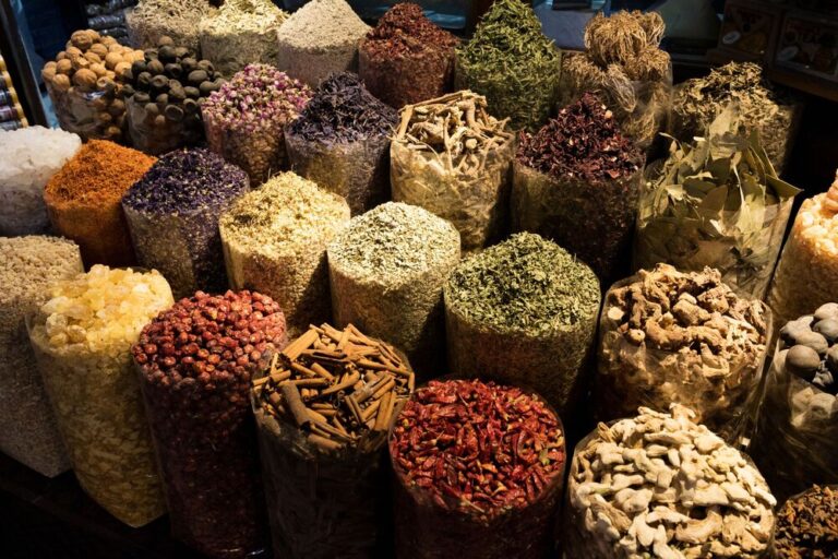 Assorted spices and herbs displayed in large, clear containers at a market.