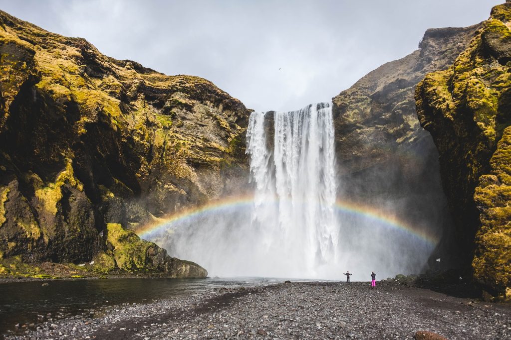 Sublime waterfall and its giant rainbow amid rocky cliffs. 
